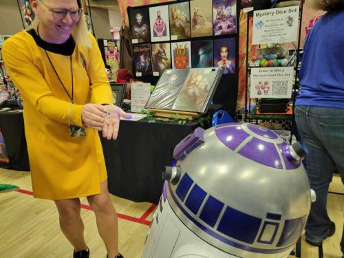 Sarah holding a LEGO R2D2 in front of a real R2D2 at Fort Collins Comic Con 2024