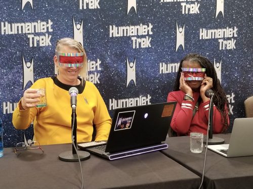 Sarah and Allie perform a live show. Both are wearing the protective eyewear required to look upon a Medusan