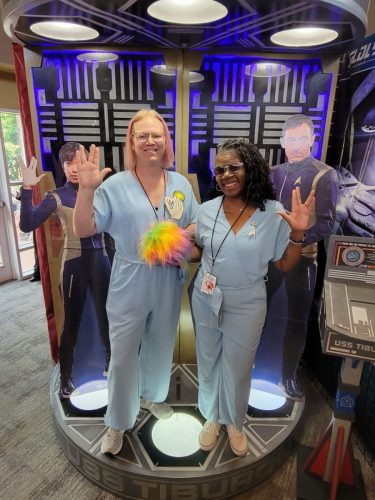 Sarah and Allie beam into the USS Tiburon Transporter Room (wearing Tantalus Penal Colony jumpsuits)