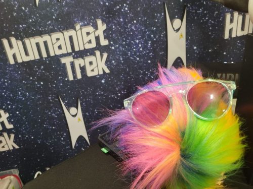 Bjo Tribble, a rainbow tribble homage to Bjo Trimble wears trendy shades.